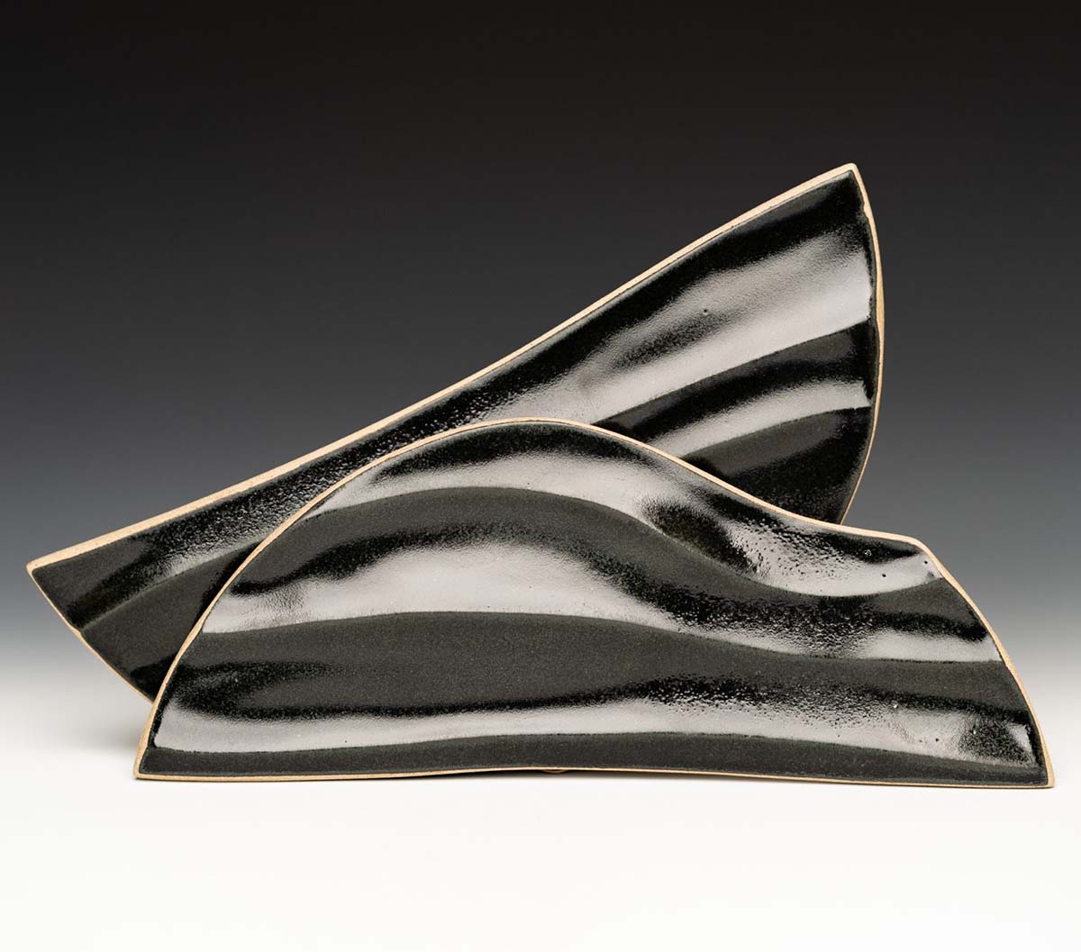 Alex Olson’s carved plates, 9½ in. (24 cm) in length, stoneware clay, black glaze, fired to cone 6 in oxidation, 2019.