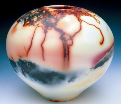 Saggar-fired Orb by Charles and Linda Riggs, 2003. 9 in. (23 cm) in width. White stoneware sprayed with white terra sigillata, polished with a soft cloth, bisque fired to cone 010, saggar-fired in a raku kiln with wood shavings, steel wool, copper, and salt.